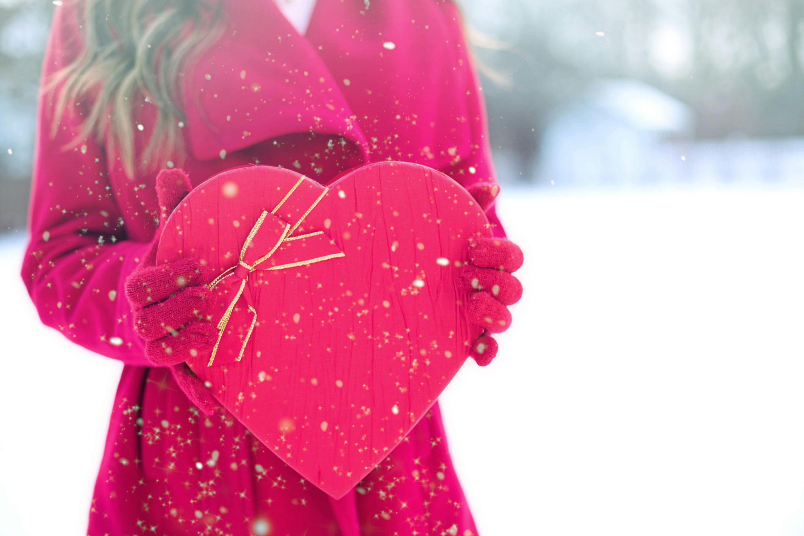 Chica con abrigo sosteniendo un corazón en la nieve
